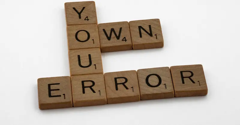 Scrabble tiles spelling 'Own Your Error' on a white background.