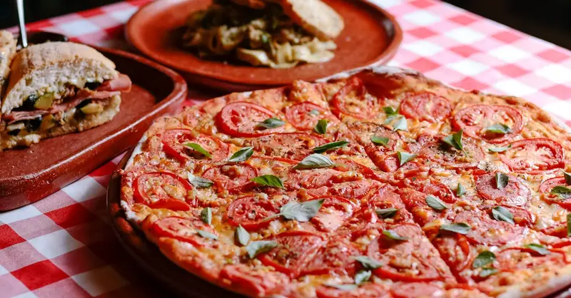 A mouthwatering Italian pizza with fresh ingredients served on a checkered table.