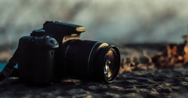 Close-up of a DSLR camera on a rocky surface, capturing soft golden sunlight at sunset.