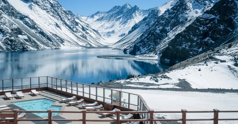 Stunning view of snow-covered Andes mountains and pristine lake in Chile with poolside foreground.