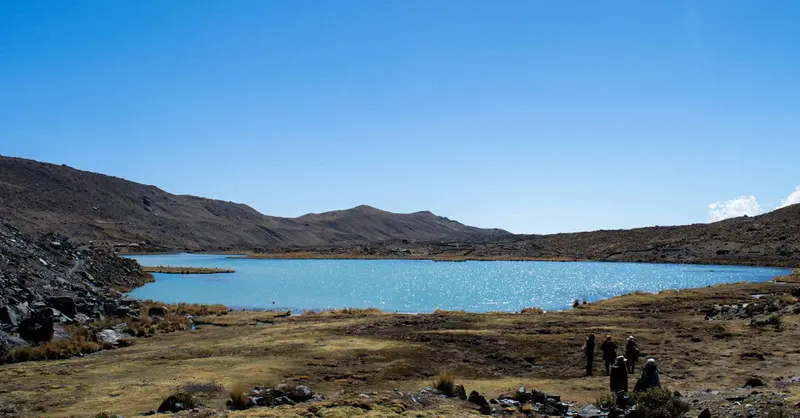Scenic view of a serene mountain lake under a clear blue sky in Cusco, Peru.