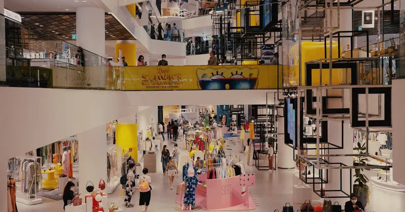 Vibrant mall filled with shoppers, contemporary decor, and stylish fashion outlets.