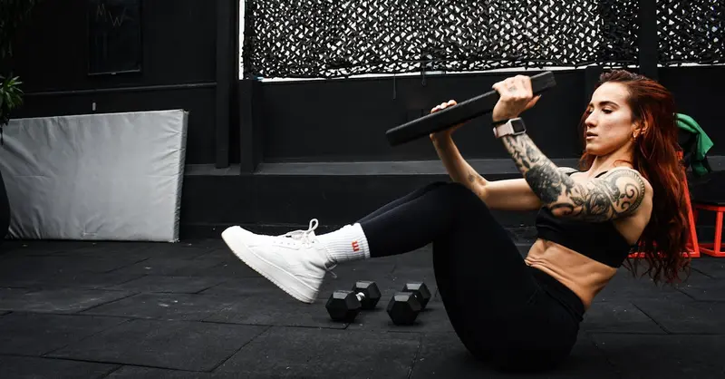 A determined woman performs a core workout in an indoor gym setting.