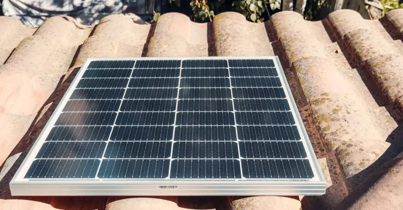 A single solar panel on a rustic tiled roof gleaming in sunlight. Eco-friendly energy.