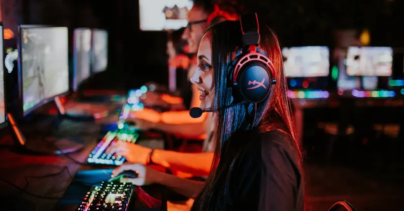 People enjoying a late-night video gaming session with headsets and RGB keyboards.