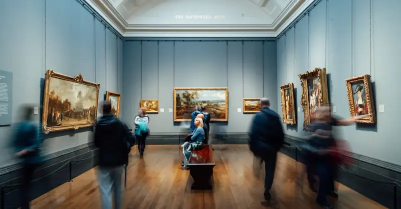 Art lovers admiring paintings in a gallery in England, showcasing culture and history.