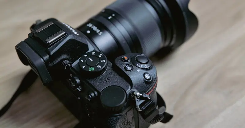 Detailed close-up of a mirrorless camera with lens on a wooden table, showcasing precision engineering.
