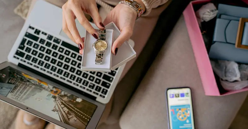 Woman unboxing a watch while online shopping using a laptop and smartphone. Perfect for lifestyle and technology themes.