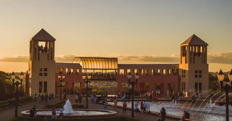 Scenic view of Parque Tanguá at sunset with fountains and a crowd in Curitiba, Brazil.