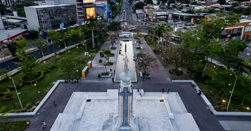 Aerial view of Monumento al Divino Salvador surrounded by cityscape of San Salvador, El Salvador at dusk.