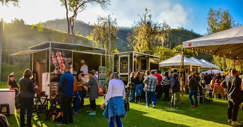 Lively outdoor street food market in Petropolis, Brazil with diverse food carts and a lively crowd.