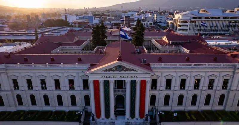 A captivating aerial shot of Palacio Nacional in San Salvador during sunset, showcasing vibrant city life and architecture.