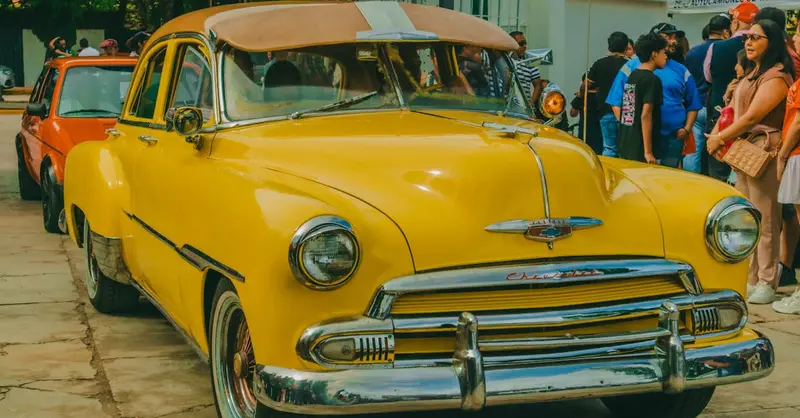 A vibrant yellow vintage car displayed at a street festival in Comitán de Domínguez, México.
