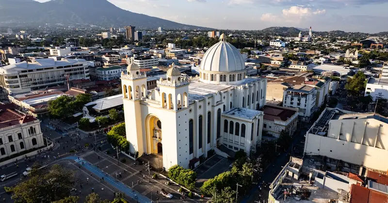 A stunning aerial view of the iconic cathedral in San Salvador, El Salvador, with surrounding cityscape and mountains.