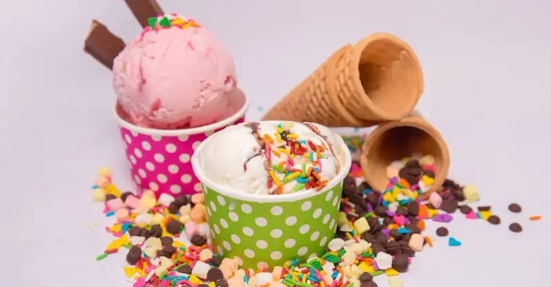 Delicious ice cream in vibrant cups with scattered sprinkles and waffle cones.