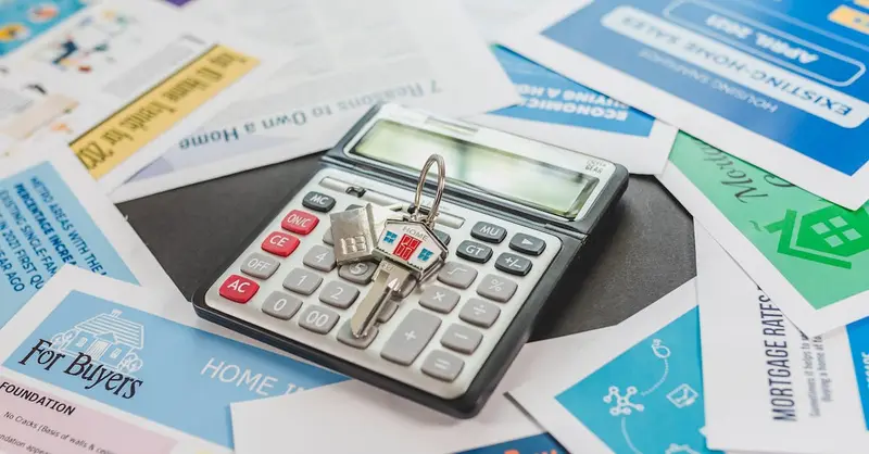 A calculator and real estate flyers depicting financial planning for home buyers.