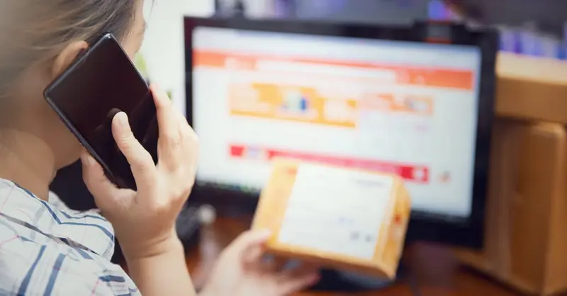 Woman multitasking by using a phone and checking an online purchase package at home.