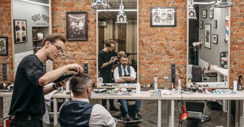 A barber expertly cutting a man's hair in a stylish, contemporary salon with exposed brick walls.