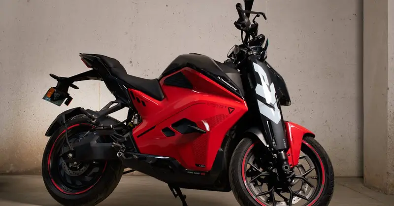 Stylish red electric motorcycle with modern design parked in a garage setting.