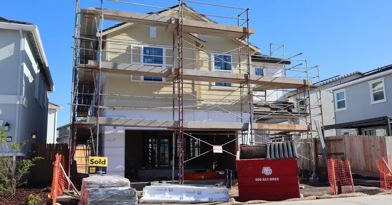 Under-construction house with scaffolding in Elk Grove, California, showing a sold sign in front.