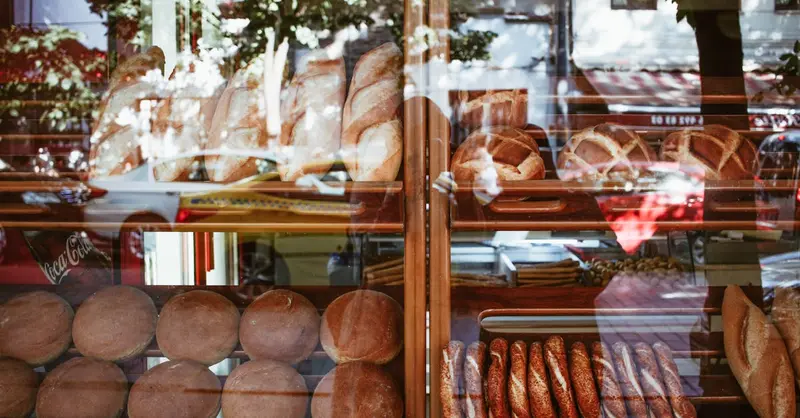 Freshly baked artisanal breads displayed in a bakery window showcasing a variety of loaves.