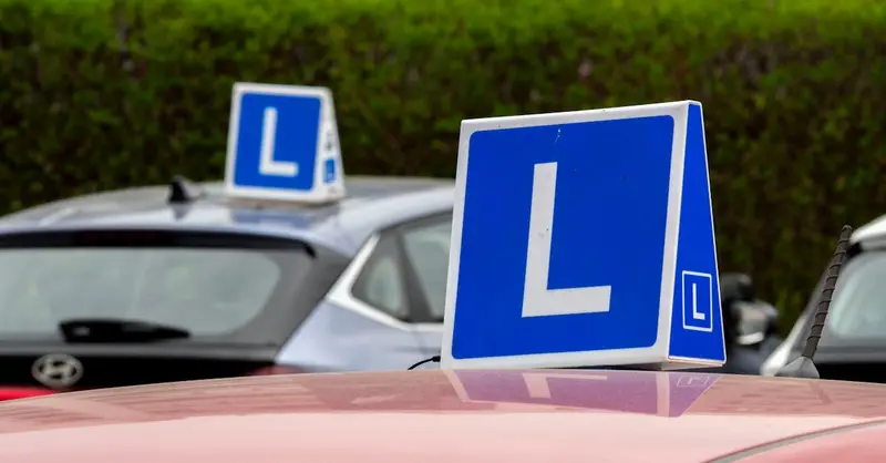 Cars with learning signs parked outdoors in Wrocław, Poland, at a driving school training area.