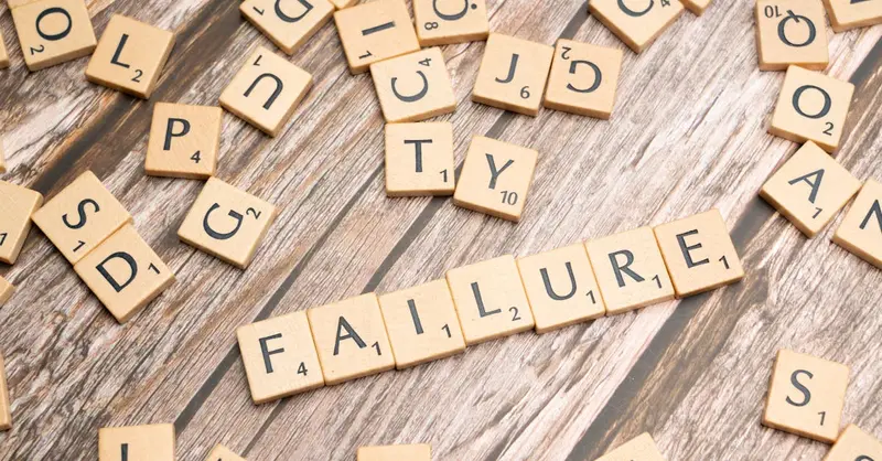Wooden letter tiles spelling 'failure' on a wooden table, representing challenges.