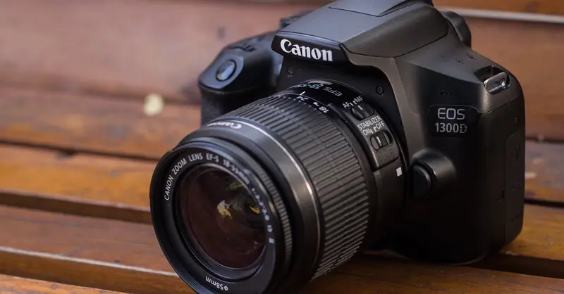 Close-up of a DSLR camera resting on a wooden bench with selective focus.