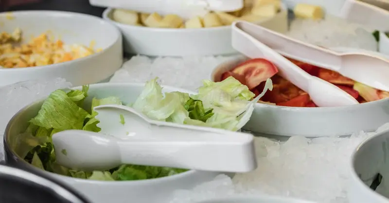 Close-up view of fresh vegetable salad bowls with ice at a buffet restaurant.
