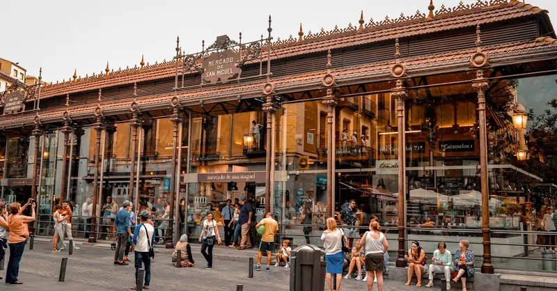 Bustling activity at Mercado de San Miguel in Madrid, a popular tourist spot with iconic architecture.