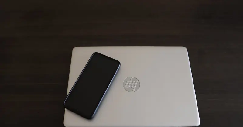Close-up of a smartphone resting on an HP laptop, symbolizing modern technology integration.