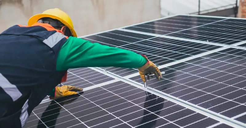 Technician installing solar panels on a rooftop for sustainable energy solutions.