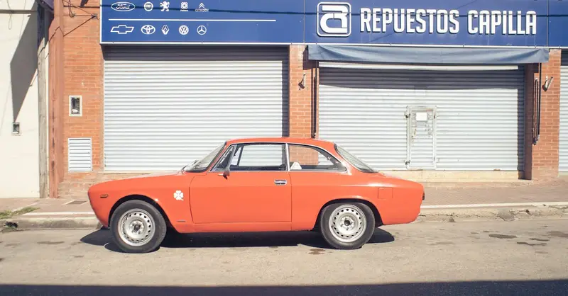 A vintage red car parked on a sunny street in Capilla del Señor, Argentina. Classic automotive nostalgia.