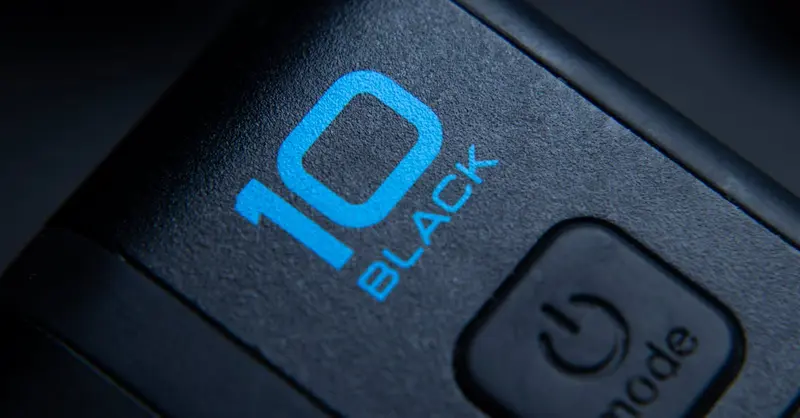 High-quality close-up of a black action camera showing the power button and model marking.