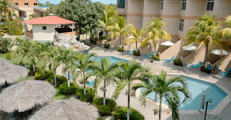 Discover a tranquil poolside oasis at a Venezuelan hotel with lush palms and inviting architecture.